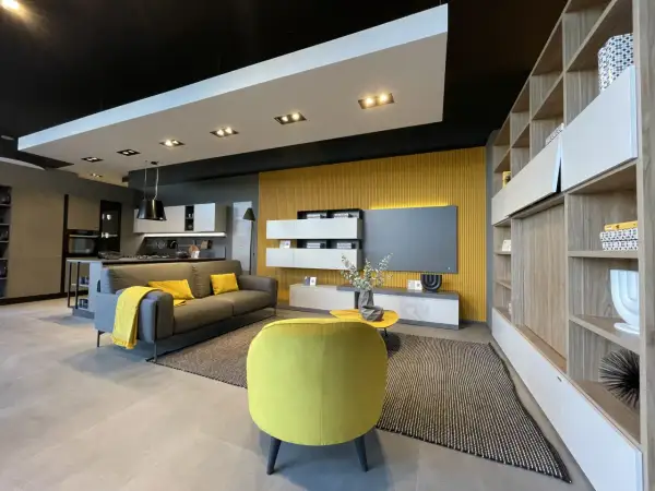 Un soggiorno moderno con divano grigio, cuscini e coperta senape colore, poltrona gialla vivace e parete di fondo color ocra.
