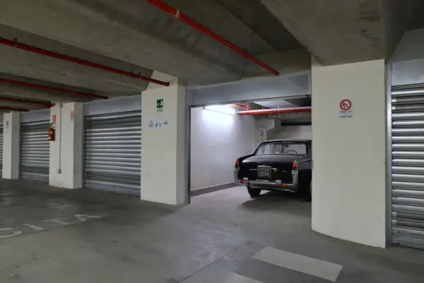 Un'auto d'epoca nera in un garage sotterraneo. Le porte a serranda chiuse e l'illuminazione suggeriscono che affittare garage conviene per proteggere il tuo veicolo.
