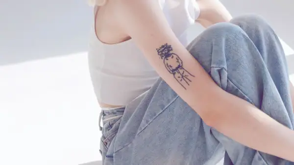 Ein Arm mit einem abstrakten Tattoo, das eine Figur mit Krone zeigt. Ein Beispiel für beste Tattoos, die Persönlichkeit ausdrücken.
