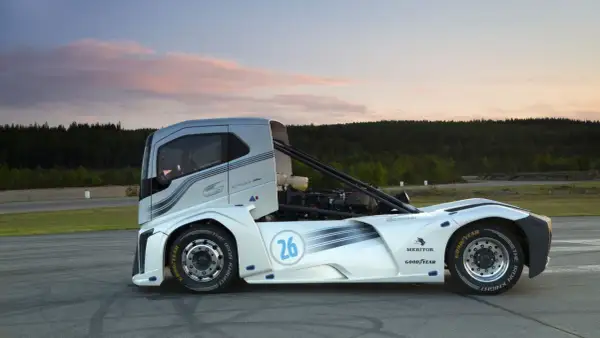 Le camion de course "The Iron Knight" blanc et argenté, numéro 26, sur une piste au coucher du soleil.