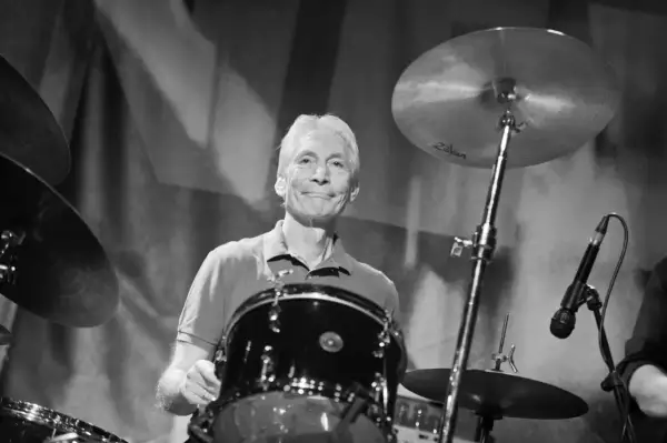 Charlie Watts, perkusista Rolling Stones, uśmiecha się za swoim zestawem perkusyjnym.