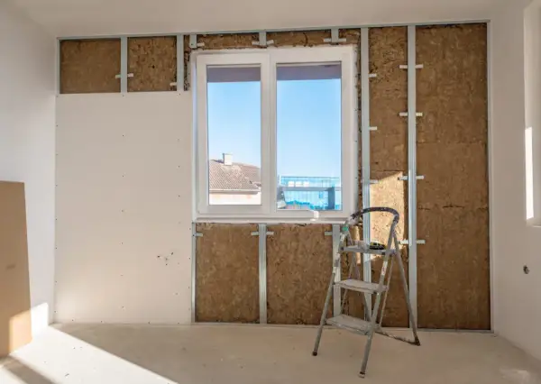 Installazione di sistemi di isolamento termico con lana di roccia e cartongesso, con una scala appoggiata al muro.
