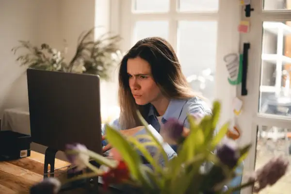 Zmarszczona kobieta przy laptopie, sfrustrowana z powodu braku połączenia z internetem.