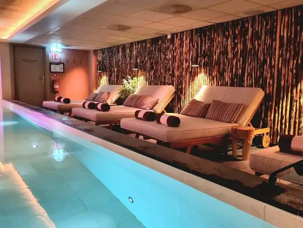 Avslappning vid poolen på ett elite hotell i Borlänge. Bekväma solstolar med kuddar och handdukar står redo vid det upplysta vattnet.