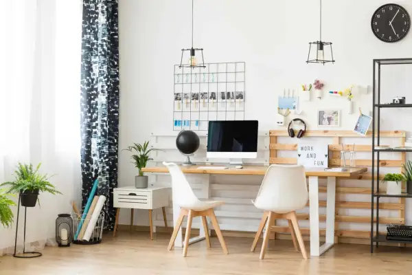 Un moderno angolo smart working con scrivania in legno, sedie bianche, computer e una lavagna luminosa con la scritta "Work and Fun".