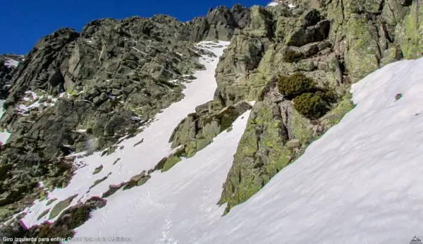 Canal de nieve y roca en la ladera de la Maliciosa, con vegetación escasa y un cielo azul intenso.