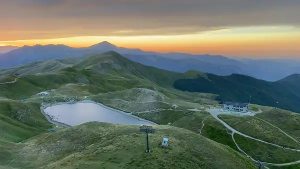 Alba sulle montagne toscane, con un lago alpino e rifugi che ricordano i borghi vicino Abetone.