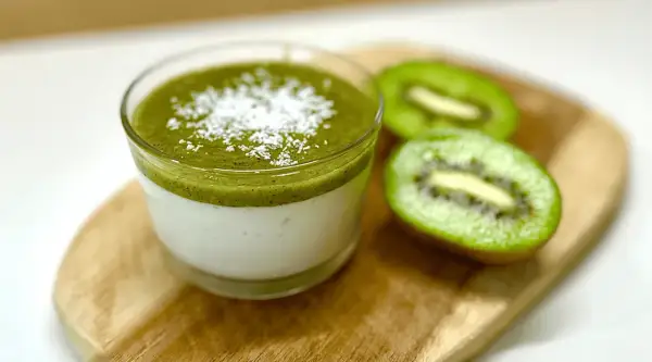 Panna cotta au lait et coulis de kiwi, saupoudrée de noix de coco râpée. Une recette légère et fruitée.