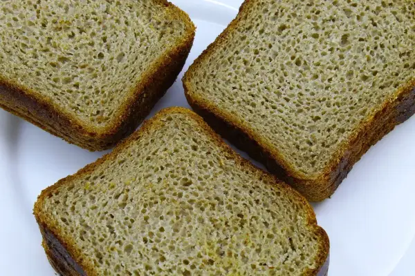 Trzy kromki chleba orkiszowego na białym talerzu. Czy mąka orkiszowa ma gluten? Tak, orkisz zawiera gluten.