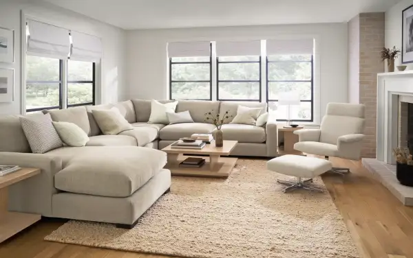 A large, neutral sectional couch is arranged in a cozy living room, showcasing different ways to arrange a sectional couch for optimal comfort and style.