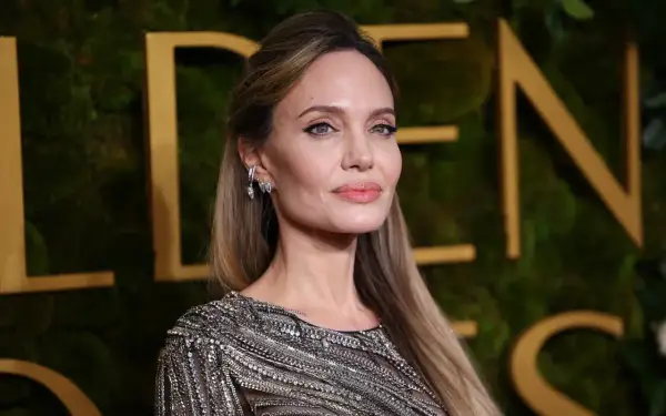 Angelina Jolie, jedna z najbardziej znanych aktorek Hollywood, w błyszczącej kreacji na tle złotych liter.
