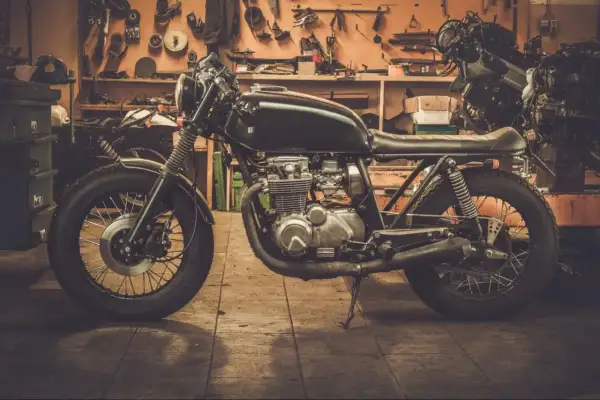 Czarny motocykl typu cafe racer w warsztacie, gotowy do sezonu.