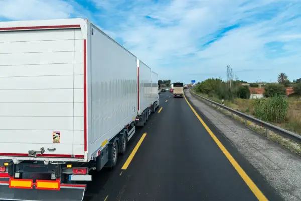 Deux semi-remorques blancs sur une autoroute, transportant chacun 44 tonnes de marchandises sous un ciel bleu.