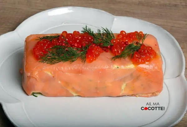 Une délicieuse terrine de saumon, garnie de perles rouges et d'aneth frais, prête à être dégustée.