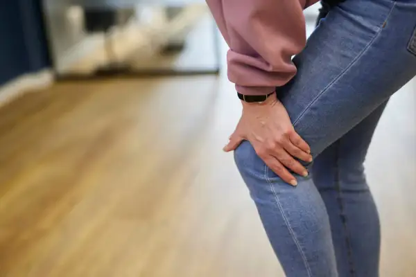 Frau hält schmerzhaft ihr Knie, was auf einen Meniskusriss hindeutet. Mögliche meniskusriss behandlung wird gesucht.