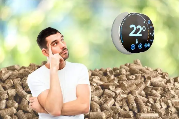 Un homme réfléchit devant un tas de granulés de bois, un thermostat connecté pour poêle à granulé affiche 22°.