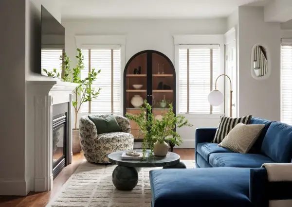 A round coffee table decor features a vase with greenery and a beaded strand, adding a natural touch to the living room.