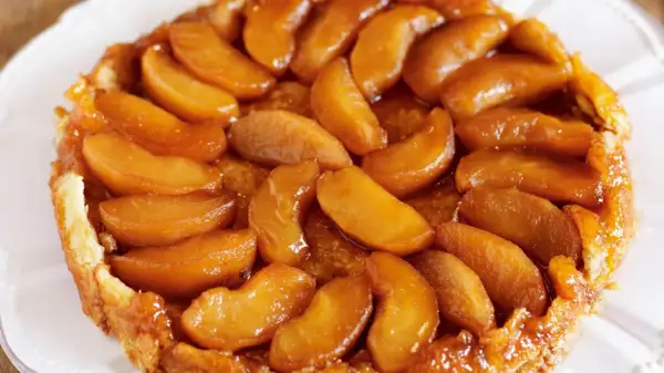 En gyllene tarte tatin med karamelliserade äppelklyftor som glänser. En klassisk fransk dessert som smälter i munnen.