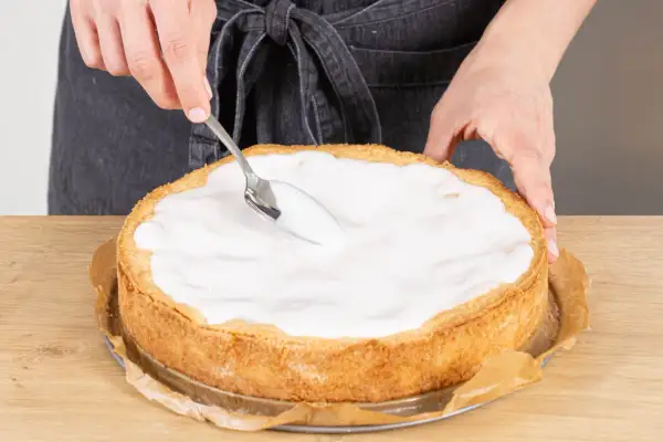 Landfrauen-Rezept: Ein goldbrauner Apfelkuchen wird mit einem Löffel mit süßem Guss überzogen.
