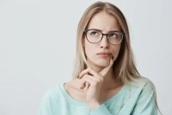 Mujer pensativa con gafas, dudando si "hice" o "hize" es correcto.