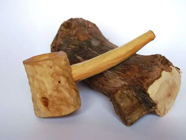 Cazoleta de brezo madera, tallada a mano, con un tronco rústico de fondo.