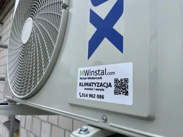 Zewnętrzna jednostka klimatyzatora z naklejką firmy MWinstal.com.