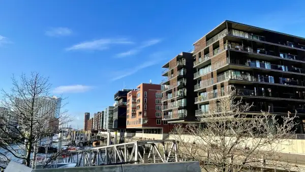 Moderne Gebäude mit Balkonen säumen das Wasser, wo Boote liegen. Die Magellan Terrassen bieten einen Blick auf die Hafencity.