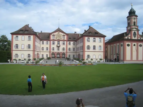 Mainau slott med sitt imponerande torn och vackra trädgårdar. En solig dag med moln på himlen.