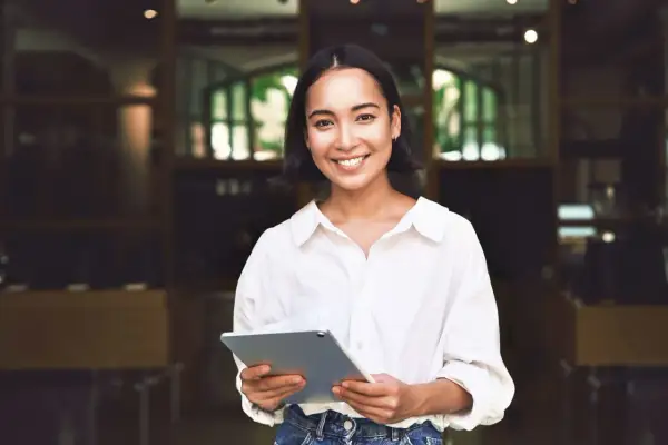 Junge Frau mit Tablet lächelt. Sie plant ihr Eventmanagement Studium dual und ist bereit für neue Herausforderungen.