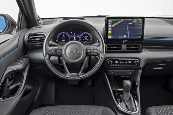 Wnętrze Toyoty Yaris Hybrid. Nowoczesny kokpit z ekranem nawigacji i cyfrowymi zegarami. Sprawdź atrakcyjną toyota yaris hybrid cena.