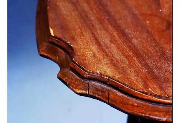 Gros plan sur le bord d'une table en bois qui se fissure, révélant les signes du temps et de l'usure.