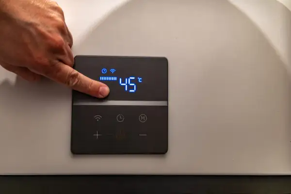 Dito un dito regola la temperatura di 45°C su un pannello di controllo di caldaie elettriche per riscaldamento.