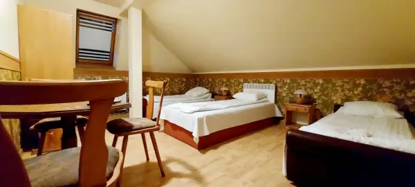 Pokój z trzema łóżkami, stolikami nocnymi i lampkami. W tle okno z żaluzjami. Wygodnie jak w domu w Korczowej.
