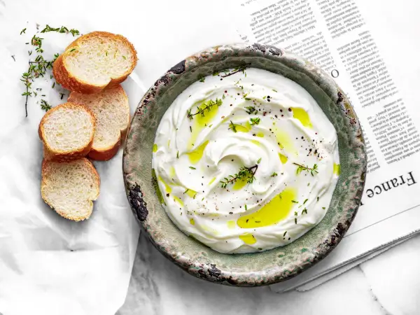 Labneh co to? Kremowy serek jogurtowy z oliwą, pieprzem i tymiankiem, podany z chrupiącymi grzankami. Idealny na śniadanie lub przekąskę.