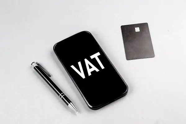 Telefon z napisem VAT, obok długopis i karta płatnicza. Ułatwia to ptu rejestracja.