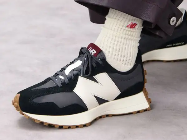 Sznurowanie butów New Balance. Ciemne sneakersy z białym logo N i brązową podeszwą.