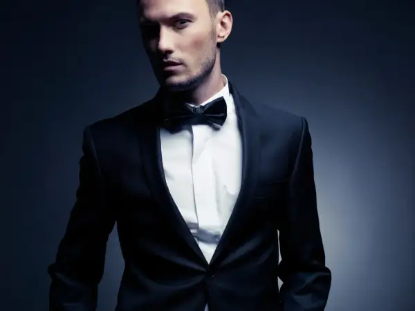 Ein Mann im eleganten Anzug mit Fliege. Der Smoking-Stil unterstreicht seine maskuline Ausstrahlung.