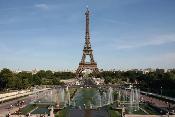 La Tour Eiffel se dresse fièrement, invitant à la découvrir. Des fontaines jaillissent, des gens se promènent, une belle journée pour monter à la Tour Eiffel.