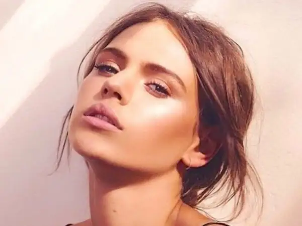 Visage d'une jeune femme au maquillage lumineux, elle pose avec un regard intense. Peut on bronzer avec du maquillage ? Sa peau semble éclatante.