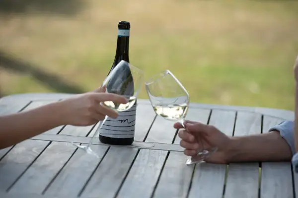 Brindisi con calici di vini delle Marche su un tavolo di legno all'aperto.
