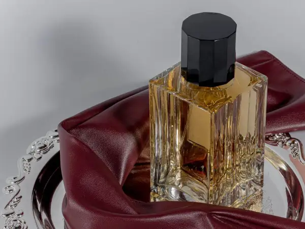 Eleganckie perfumy z lat 2000. w szklanej butelce z czarną nakrętką, na ozdobnej tacy z bordową skórką.