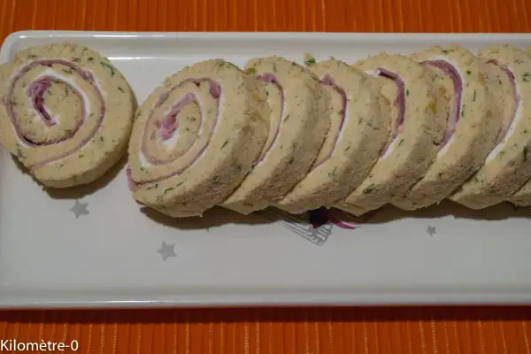 Un roulé au jambon fromage, coupé en tranches, garni de fromage frais et de fines herbes. Parfait pour un apéritif.