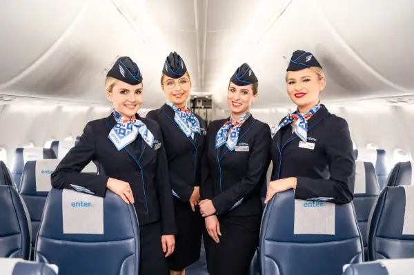 Uśmiechnięte stewardessy Enter Air w granatowych mundurach, gotowe do obsługi lotów czarterowych.