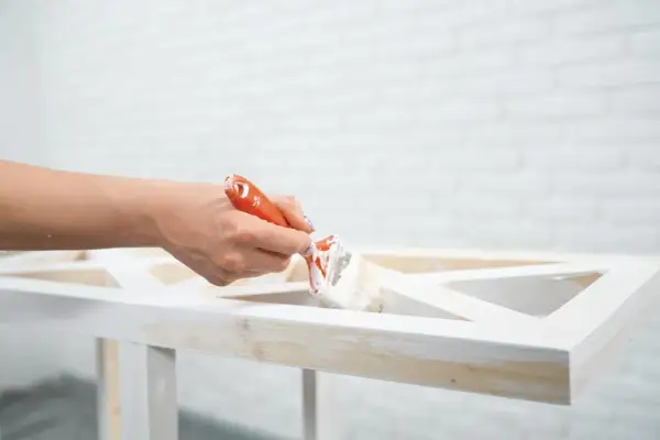 Mano che dipinge un mobile in legno con vernice a gesso, per un effetto shabby chic.