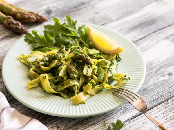 Pappardelle ze szparagami i zielonym pesto, udekorowane rukolą i cytryną. Pyszne danie, które zachwyci każdego miłośnika makaronu.