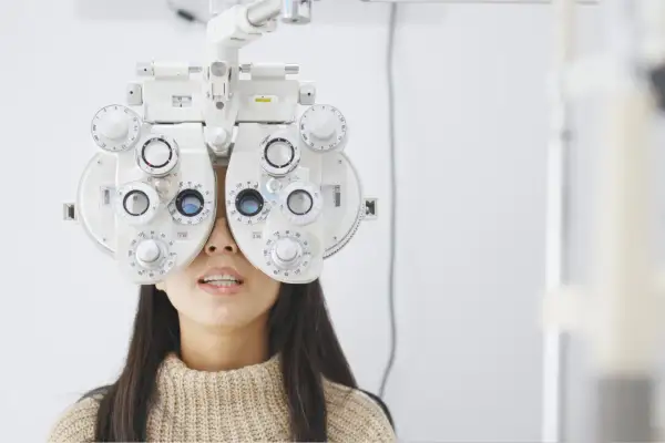 Kobieta z foropterem na twarzy, badana przez optometrystę. Ortoptysta ocenia jej wzrok.