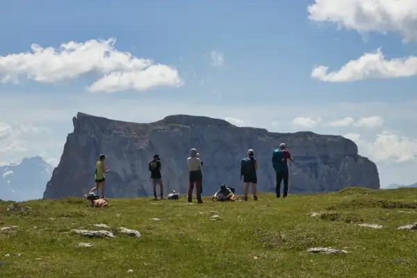 Groupe de randonneurs admirant un impressionnant plateau rocheux lors d'un trek dans le Vercors. Ciel bleu et nuages blancs.