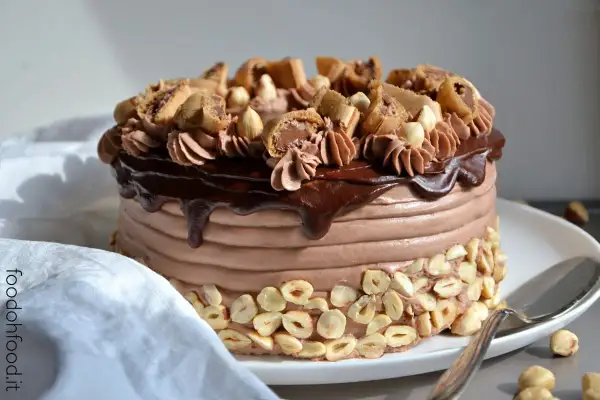 Torta di buon compleanno al cioccolato e nocciole, con glassa lucida e decorazioni golose.
