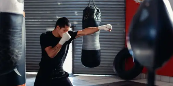 A boxer trains in a gym, practicing the sweet science of boxing with a punching bag.