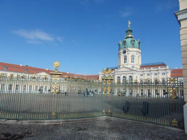 Zamek Charlottenburg, cel jednodniowej wycieczki z Poznania. Złote zdobienia bramy i błękitne niebo.